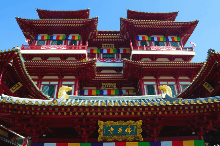 Buddha Tooth Relic Temple in Singapore’s Chinatown, a majestic Tang-style structure with red-and-gold tiered roofs, prayer flags, and ornate balconies—symbolizing the spiritual heart of tradition amid the district’s vibrant cultural evolution.