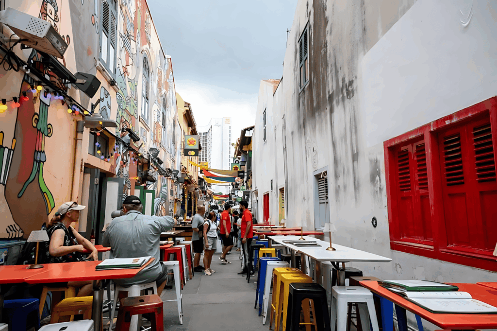 Vibrant alleyway in Singapore filled with colourful shophouses, outdoor restaurants, and hawker stalls offering good food, located in the cultural melting pot of Singapore neighbourhoods such as Chinatown, Kampong Gelam, Little India, Joo Chiat, Tiong Bahru, and Holland Village. This bustling area, easily accessible and easily accessed with easy access from Changi Airport, is within walking distance for a trip to numerous restaurants, bars, malls, and shopping streets. Visitors can explore and rest at Marina Bay, Clarke Quay, Robertson Quay, Orchard Road, Dempsey Hill, and the financial district, or head south to Sentosa Island and Sentosa Cove hotels, north to Bukit Timah, Bukit Batok, and Bukit Panjang residential areas, east to East Coast Park, Pasir Ris, Eastpoint Mall, and Paya Lebar, and west to nature lovers’ trails. Highlights include local Peranakan culture, fresh produce markets, Singapore River views, Singapore Zoo, and neighbourhoods popular with young couples, expats, and residents. This city offers the best neighbourhood options for nightlife, culture, history, food, and island escapes, making it a point to visit for those who want to indulge in the country’s world-class attractions and heritage houses.