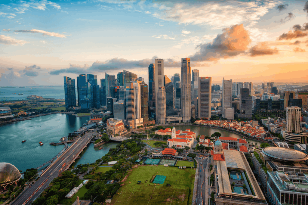 Stunning sunset view of Marina Bay in Singapore, showcasing the financial district skyline, Marina Bay Sands hotel, Singapore River, and surrounding city attractions in the melting pot of Singapore neighbourhoods. Easily accessible and easily accessed with easy access from Changi Airport, this bustling area is within walking distance to numerous restaurants, hawker stalls serving good food, bars, malls, and shopping streets. Visitors can explore local Peranakan culture, colourful shophouses, and cultural landmarks in Chinatown, Kampong Gelam, Little India, Joo Chiat, Tiong Bahru, Holland Village, Robertson Quay, Clarke Quay, Orchard Road, and Dempsey Hill. From fresh produce markets in residential area houses of Bukit Timah, Bukit Batok, Bukit Panjang, Pasir Ris, and Paya Lebar, to nature lovers’ escapes at East Coast Park, Sentosa Island, and Sentosa Cove hotels, each neighbourhood offers unique culture, history, and nightlife. Highlights include the Singapore Zoo, Eastpoint Mall, island getaways, and neighbourhoods popular with young couples, expats, and residents. This guide to the country’s towns invites travellers to walk, visit, explore, and indulge in the best neighbourhoods located north, south, east, and west, filled with world-class attractions and rich cultural heritage.
