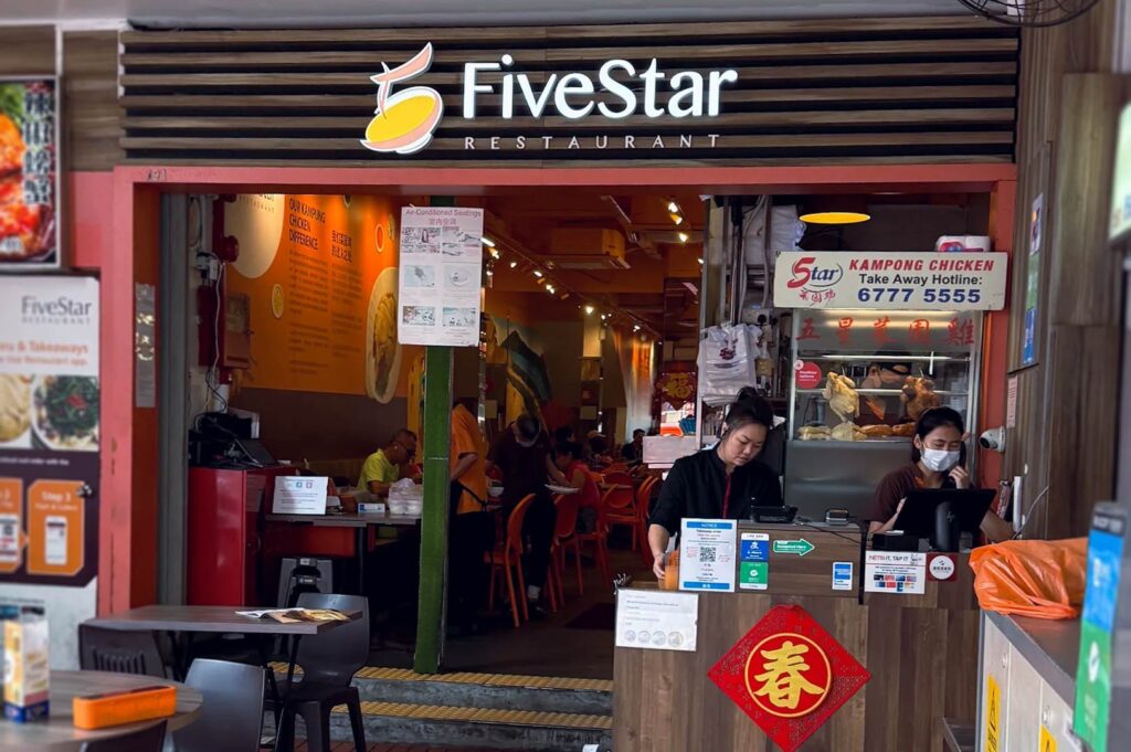 ive Star Restaurant storefront featuring an orange interior, illuminated signage, and a takeaway counter displaying kampong chicken and menu boards.