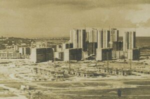 Historical photograph of Marine Parade, Singapore, showing high-rise residential blocks under construction surrounded by cleared land and low-rise building works, with the coastline visible in the background.