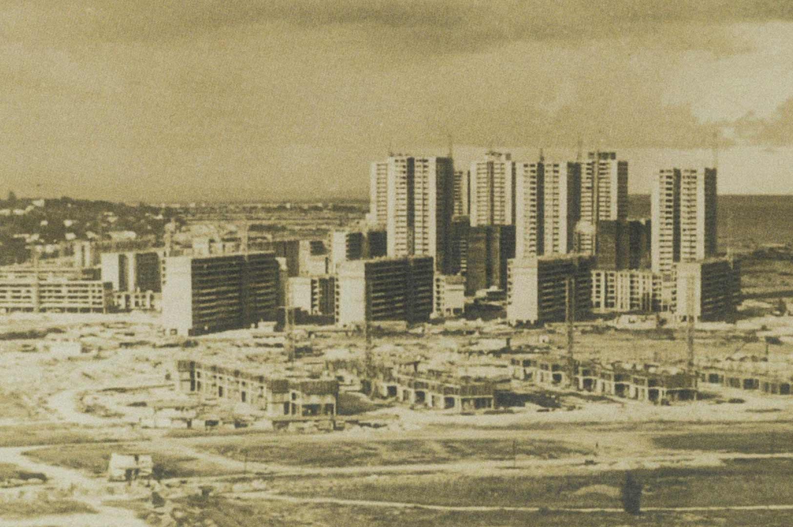 Historical photograph of Marine Parade, Singapore, showing high-rise residential blocks under construction surrounded by cleared land and low-rise building works, with the coastline visible in the background.