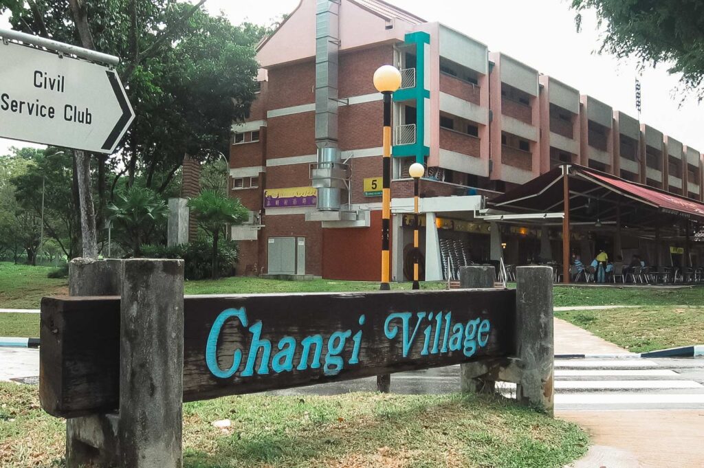 Changi Village sign in front of residential blocks and shops near the Civil Service Club.