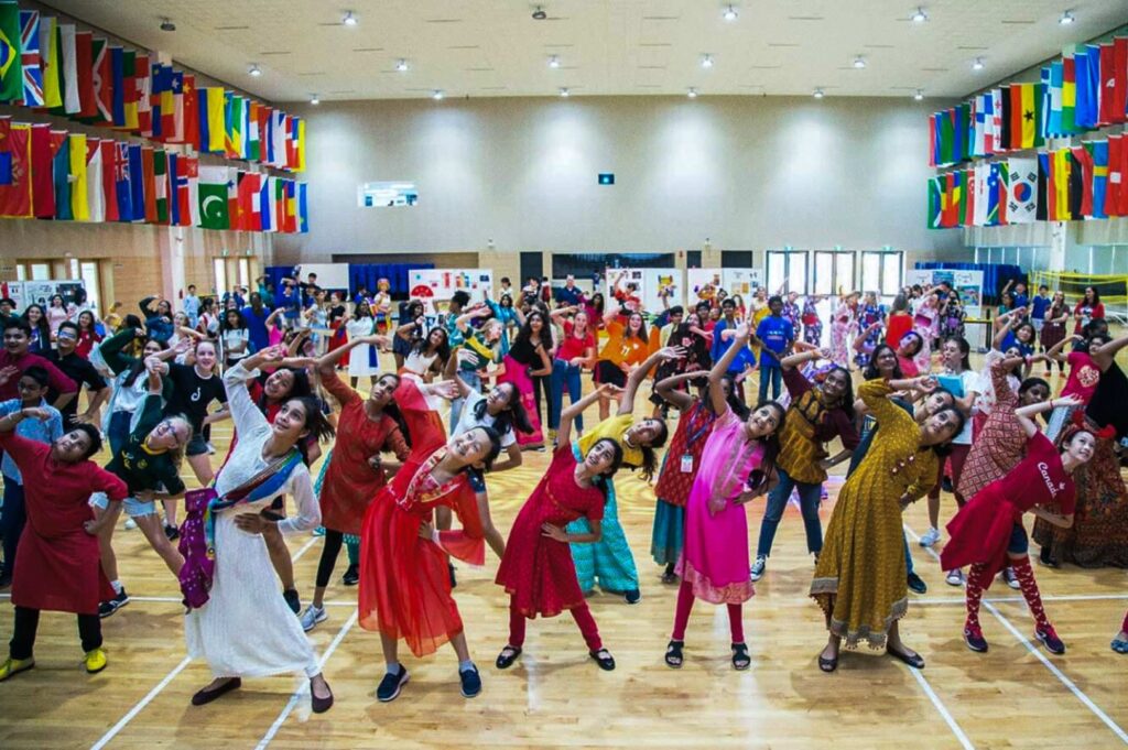 Large cultural dance event with children performing in colorful traditional outfits.