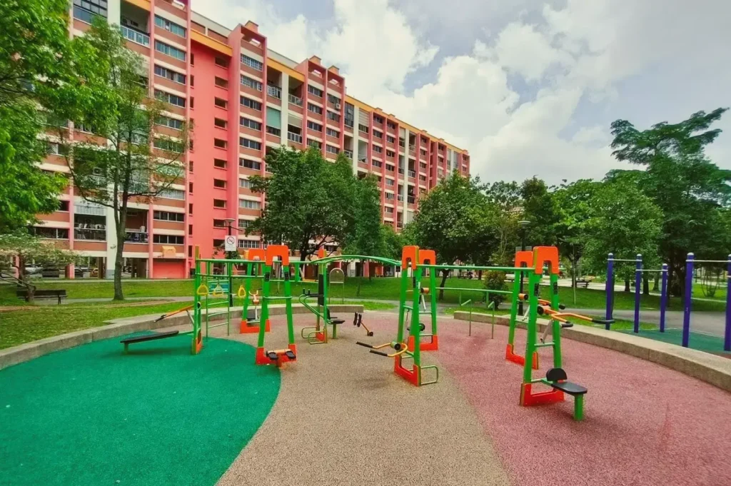 Community fitness corner in Tampines, Singapore with outdoor exercise equipment set within a neighbourhood park near residential blocks.
