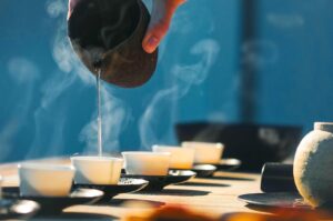 Hot tea being poured into small teacups in a ceremonial setup.