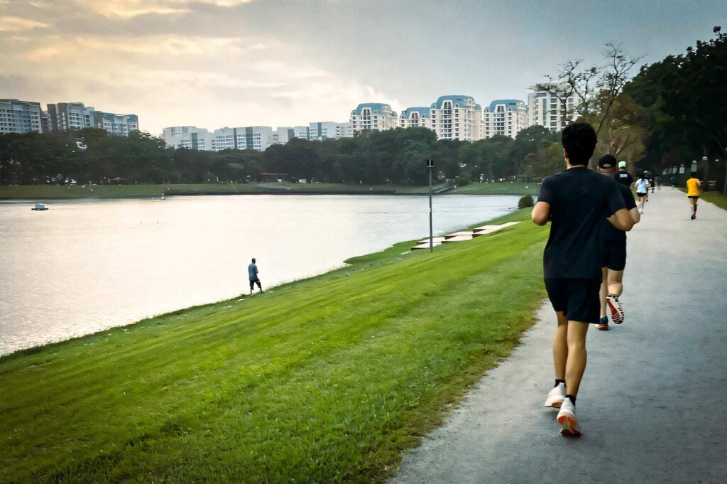 Joggers running along the lakeside path at Bedok Reservoir Park.