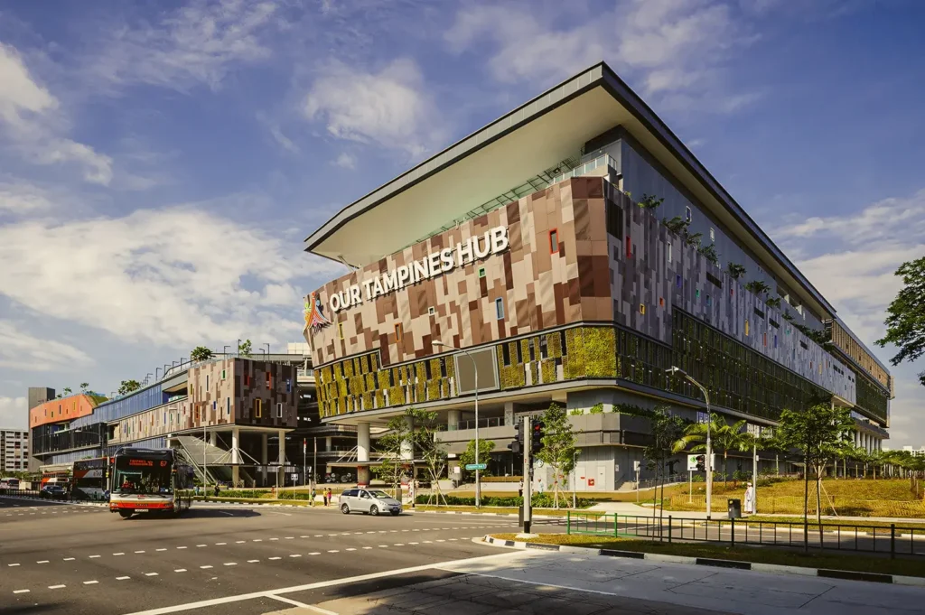 Our Tampines Hub in Singapore, a large integrated community and lifestyle complex with modern architecture along a major road junction.