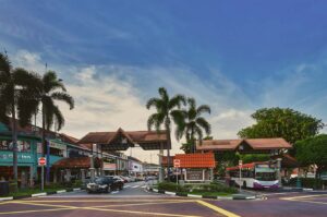 Serangoon Garden Circus Singapore landmark with Sushi Tei, Kid Math, Lee storefronts, palm landscaping, and public bus 315."