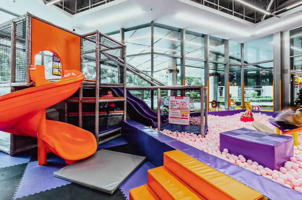 Wide‑angle interior shot of a colorful indoor playground featuring slides, climbing structures, padded platforms, and a ball pit, highlighting family‑friendly indoor activities and children’s play spaces.