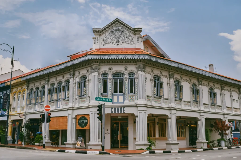 Wide-angle corner shot of a modern café (Natsu) restored colonial Peranakan shophouse on Koon Seng Road, showcasing ornate facade, arched windows, and heritage architecture in Katong Singapore.