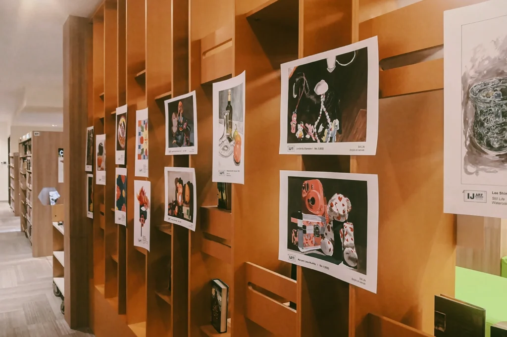 Side-angle perspective shot of library wall exhibition featuring community artwork and cultural displays, representing cultural programming and creative engagement in Singapore libraries