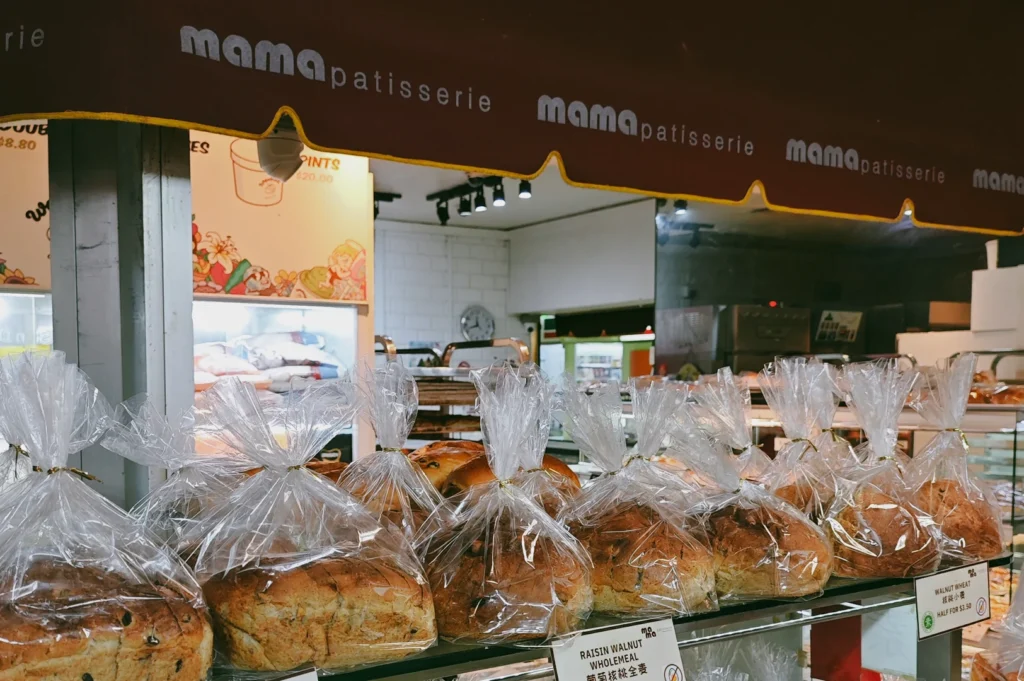 Close-up eye-level shot of Mama Patisserie bakery display at Fortune Centre, featuring packaged vegan bread and pastries on shelves