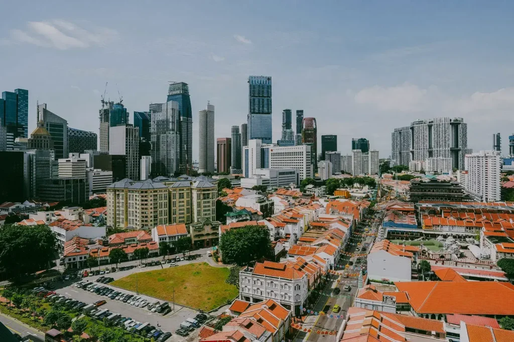 High-angle panoramic view of Tanjong Pagar showing historic red-roof shophouses in the foreground and Singapore’s modern skyline in the background, highlighting the district’s blend of heritage and progress