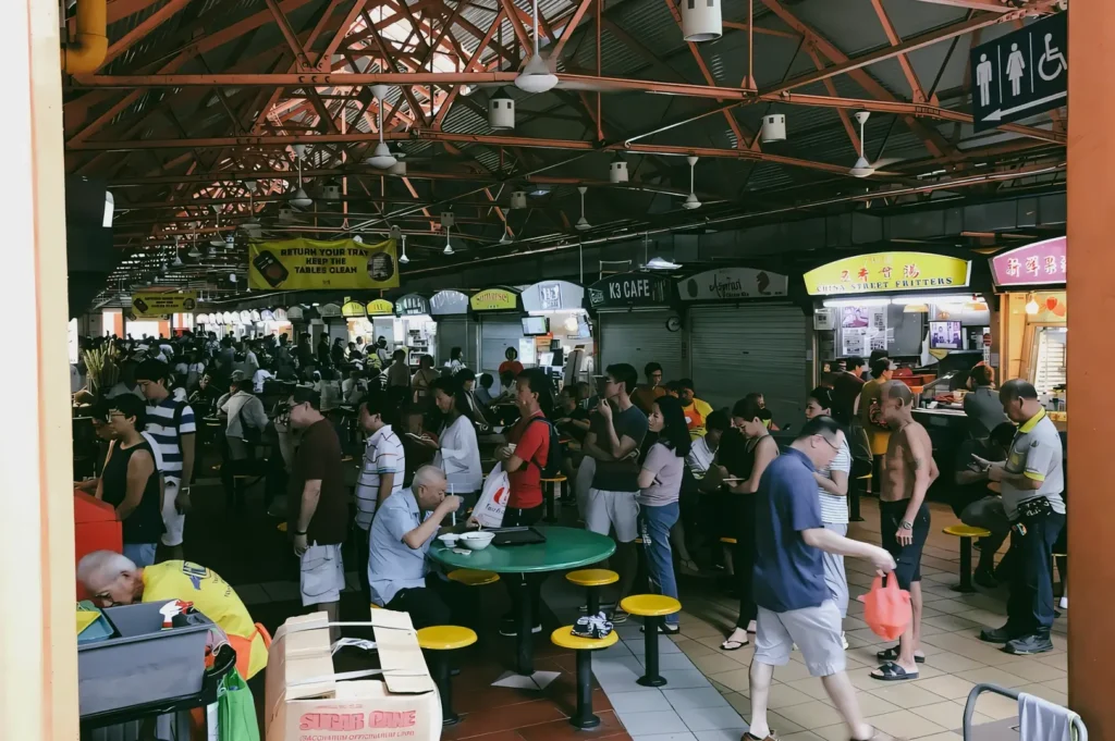 Wide-angle view of a crowded Maxwell Food Centre at lunchtime, showing weekday dining routines, communal seating, and fast-paced food culture.