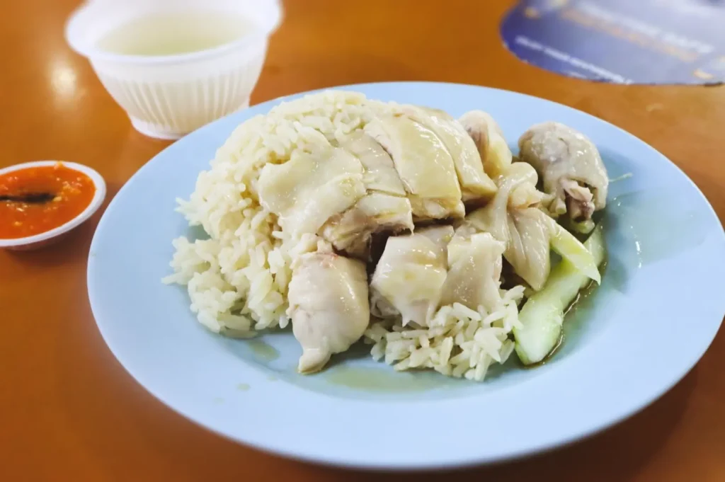 Close-up top-down view of Hainanese chicken rice with chili sauce, a classic weekday lunch dish served quickly at Singapore hawker centres.