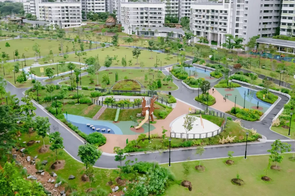 High-angle wide shot of Tampines Boulevard Park Singapore featuring landscaped neighbourhood park, playground areas, winding walking paths, and surrounding residential blocks, highlighting accessible community spaces and urban green design.