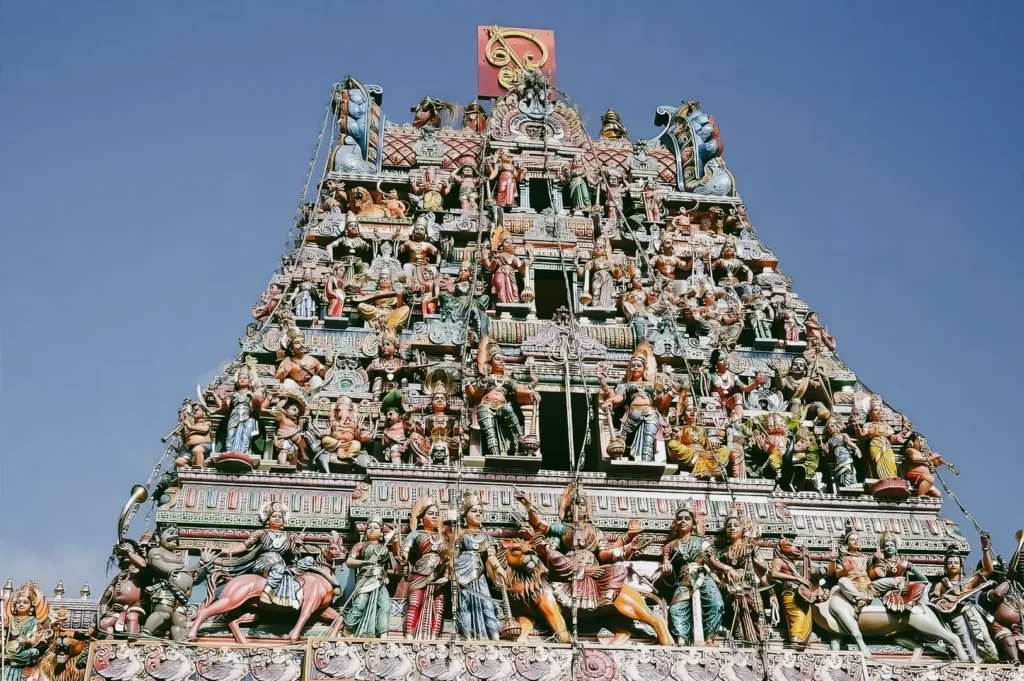 Low-angle close-up shot of Sri Veeramakaliamman Temple gopuram tower covered in colorful Hindu deity sculptures, highlighting traditional South Indian temple architecture in Little India Singapore