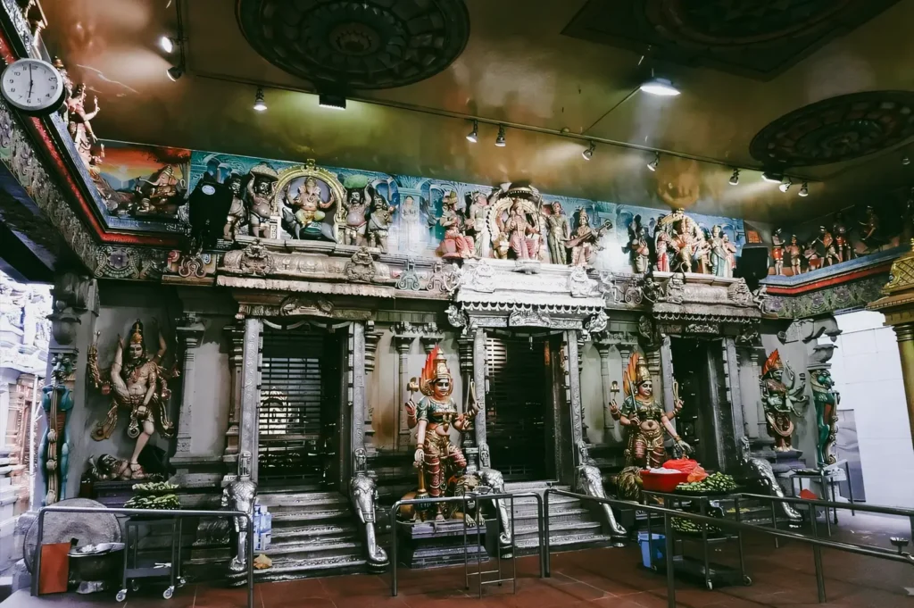 Eye-level wide interior shot of Sri Veeramakaliamman Temple shrine with detailed Hindu deities and ornate carvings, showcasing spiritual rituals and religious heritage in Little India Singapore