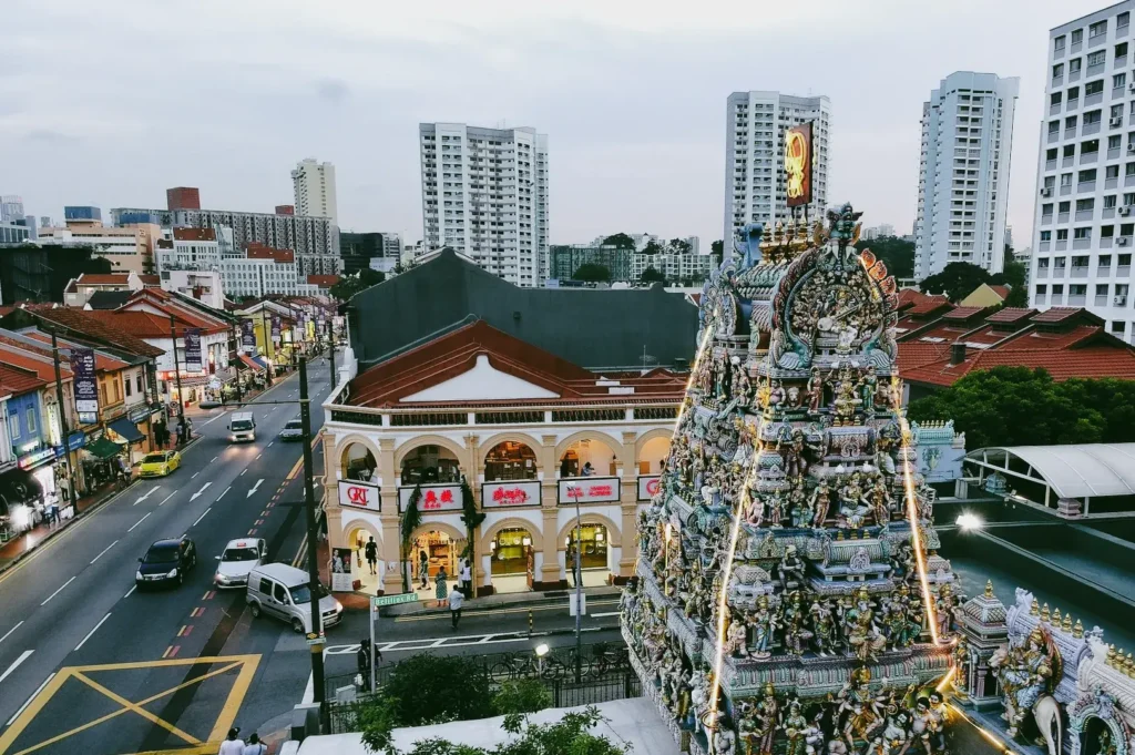 High-angle wide shot overlooking Sri Veeramakaliamman Temple and Serangoon Road with surrounding buildings, illustrating the integration of Hindu temple life within Little India Singapore urban landscape