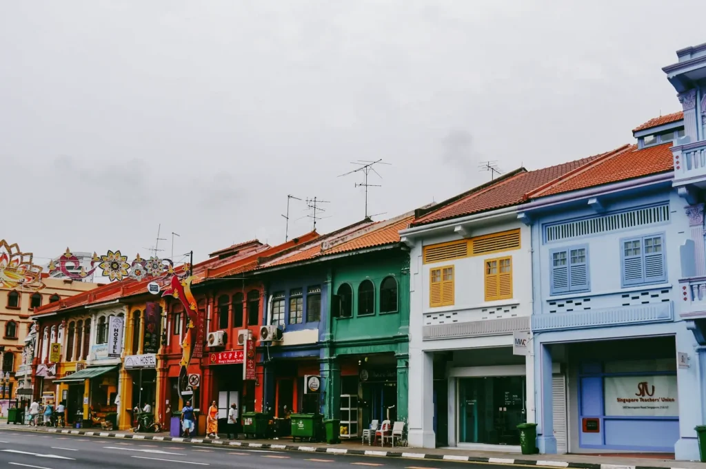 Eye-level wide street shot of colorful heritage shophouses along Little India Singapore, featuring traditional architecture and cultural district streetscape in daytime