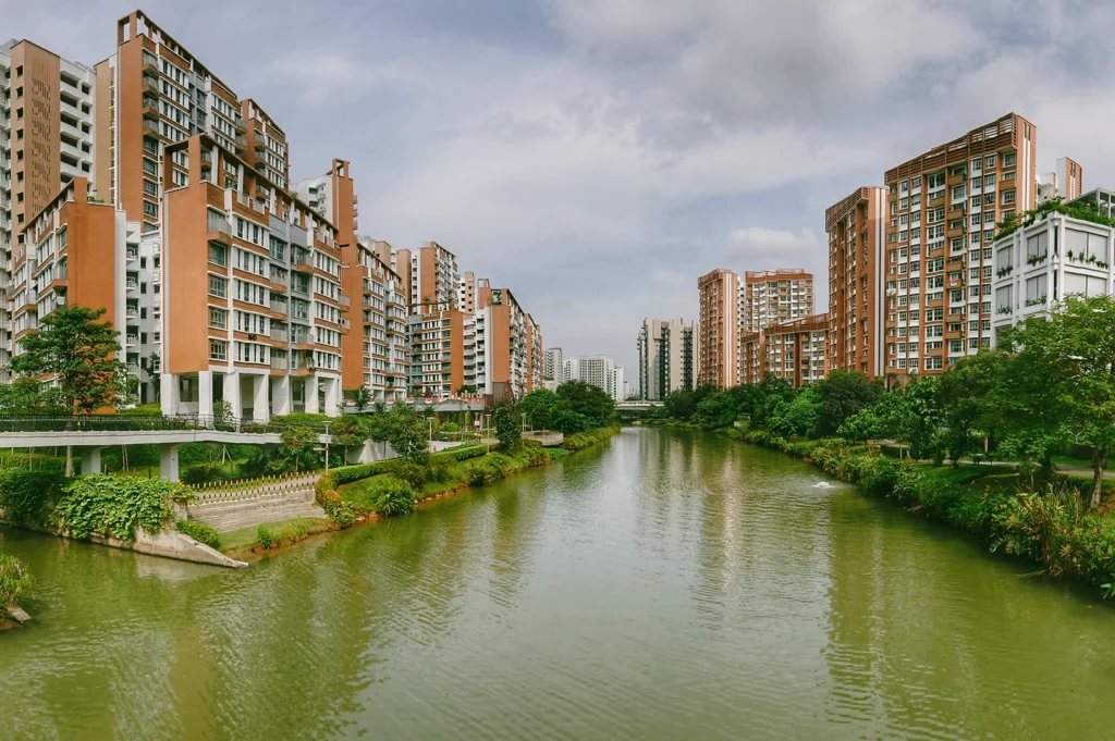 Centered eye-level view of Punggol Waterway lined with modern residential buildings and green embankments, illustrating sustainable waterfront housing and eco town infrastructure in Singapore