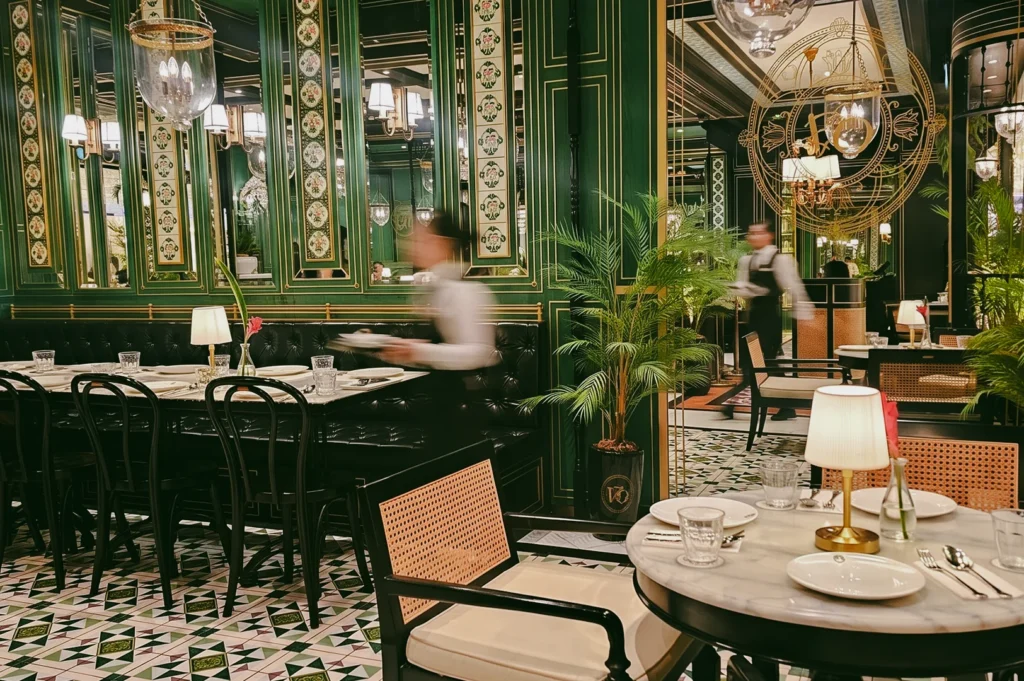 Interior of Violet Oon ION Orchard showcasing Peranakan heritage design with rattan seating and marble tables, captured in wide-angle eye-level dining room shot