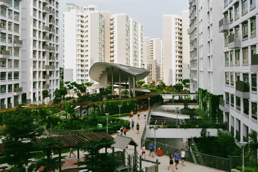 Elevated wide-angle view of Punggol Eco Town residential courtyard with modern HDB flats, landscaped greenery, pedestrian walkways, and a central pavilion, showcasing sustainable urban design and community living in Singapore