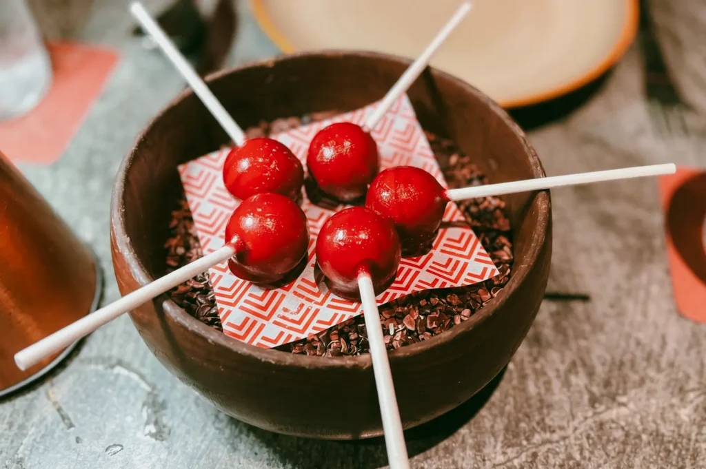 Overhead macro shot of CÉ LA VI Singapore foie gras hibiscus lolli with glossy red coating, showcasing modern Asian fine dining presentation